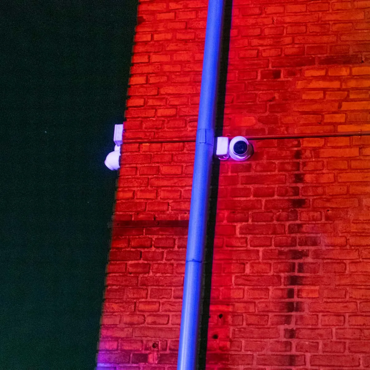 Red and blue video mapping projected onto an old brick building at night.