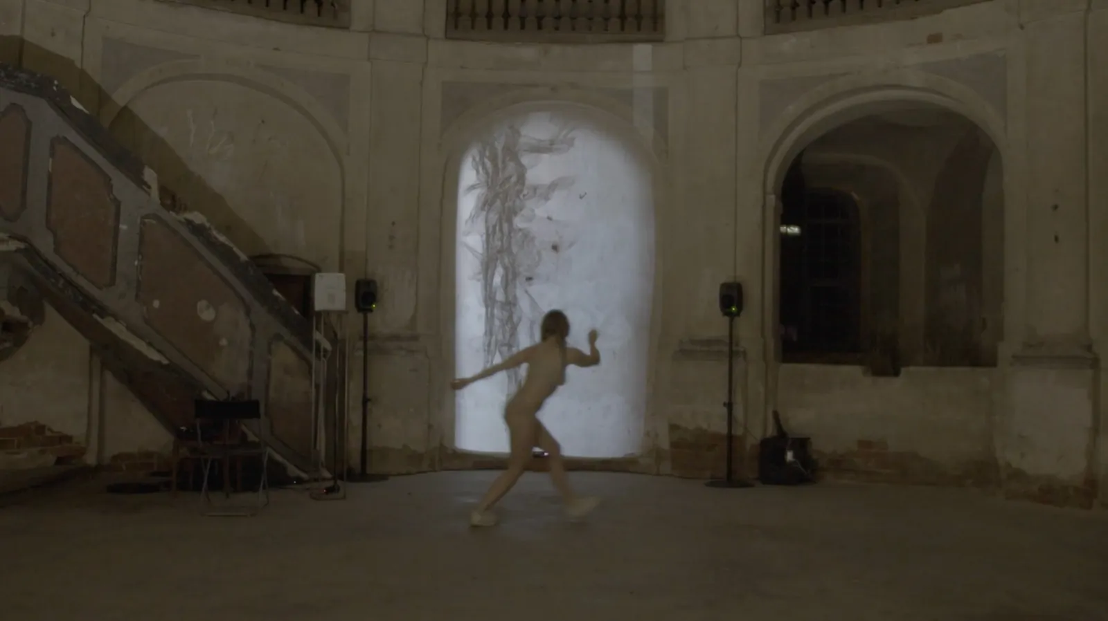 The dancer mid-movement in front of the projection.