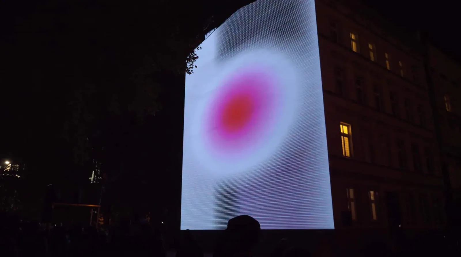 Abstract red and white animation projected across a dark building facade at night.