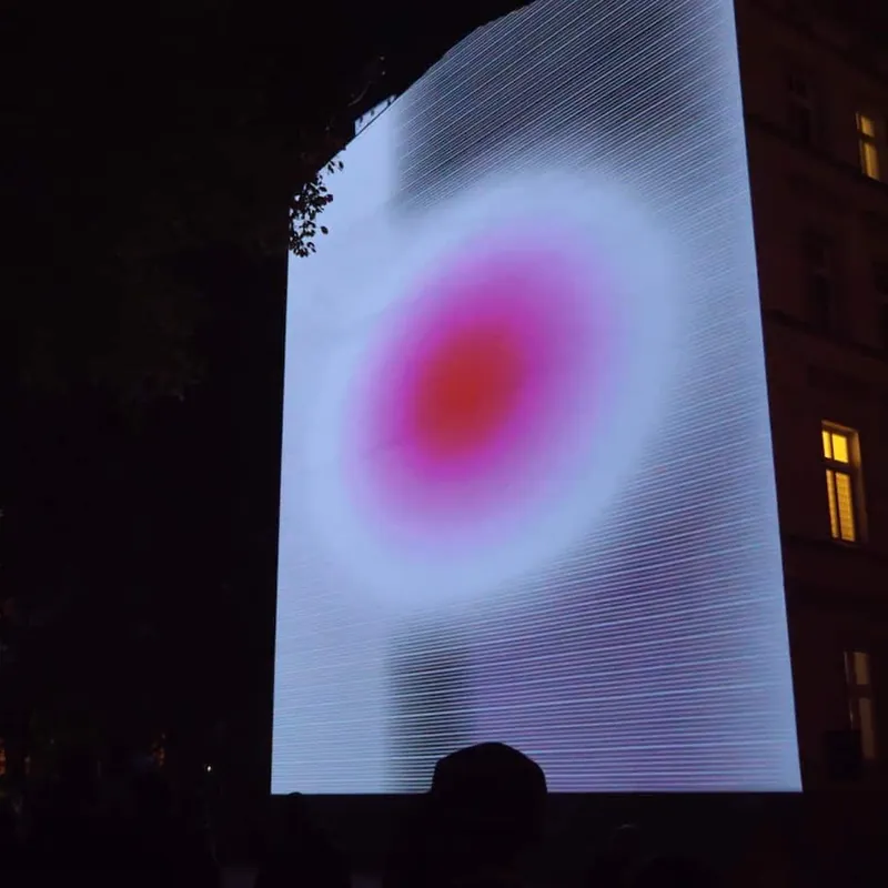 Abstract red and white animation projected across a dark building facade at night.