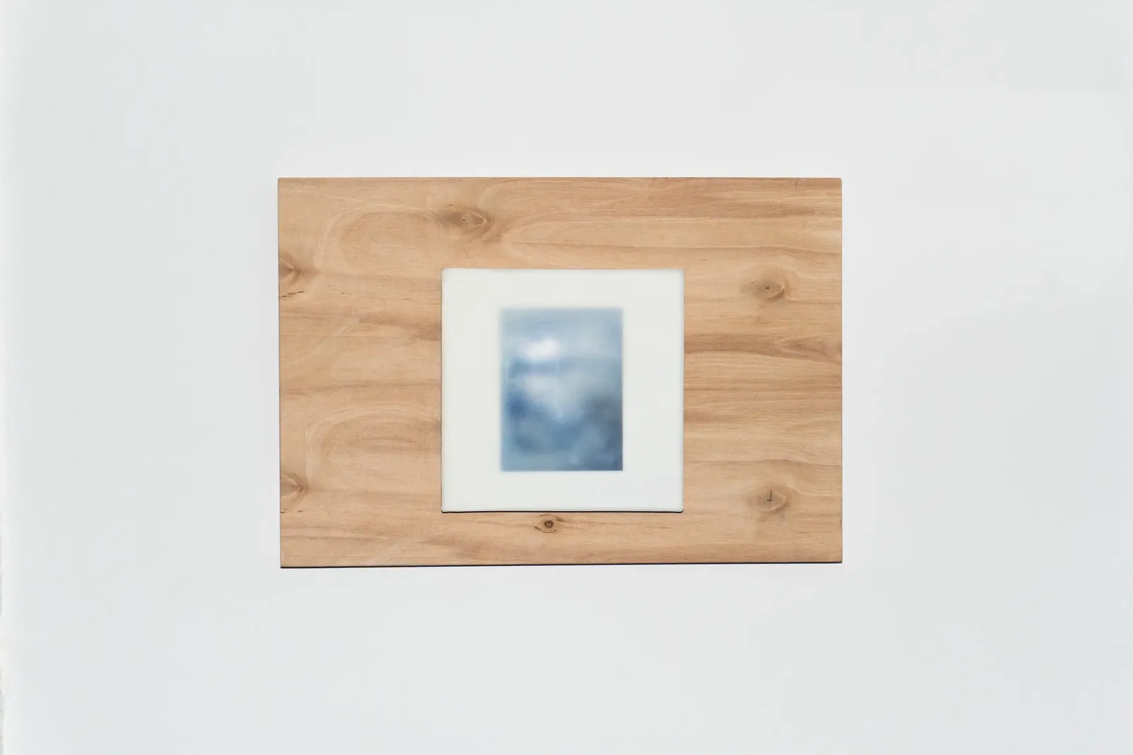 A small photograph set into a plywood panel with a pale tile surround, hung on a white wall.