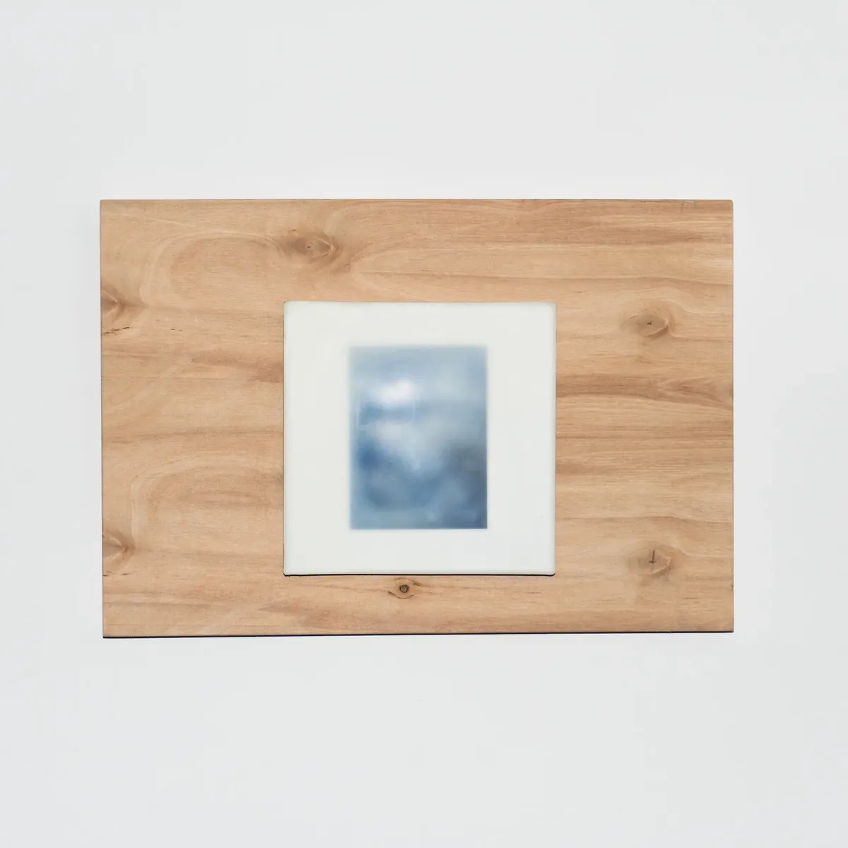 A small photograph set into a plywood panel with a pale tile surround, hung on a white wall.