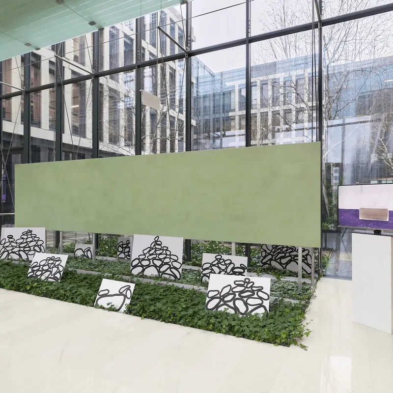 A long green painting hung above painted stone panels set in ivy, in a glass-walled lobby.