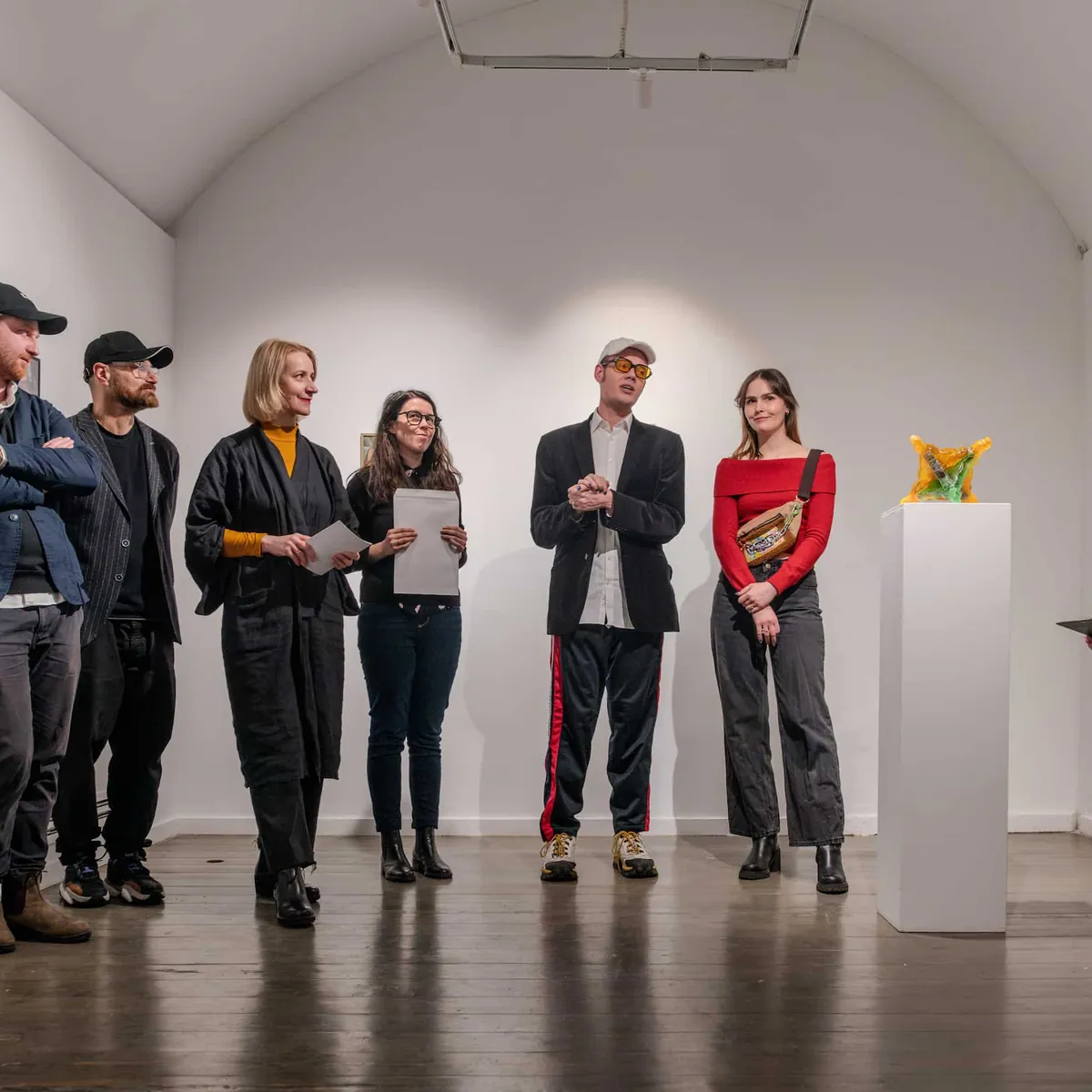 Visitors standing in a white vaulted gallery at the exhibition opening.